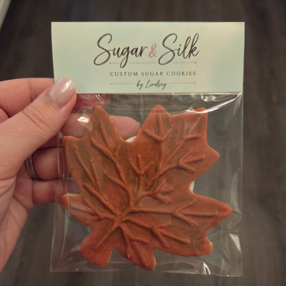 A maple leaf cookie in a clear bag with the Sugar & Silk label